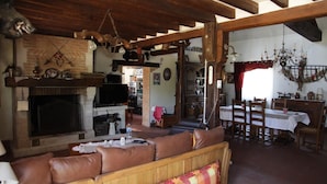 A rustic living room with a fireplace, wooden furniture, and a dining area. - La Grange 41 (Vouzon)
