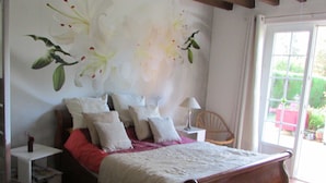 A bedroom with a bed, pillows, a nightstand, a lamp, and a chair. - La Grange 41 (Vouzon)