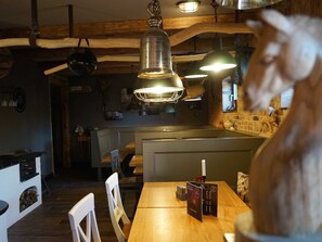 Ein Restaurantinneres mit Holzbalken, Pendelleuchten, einem Kamin und einem Menüständer.