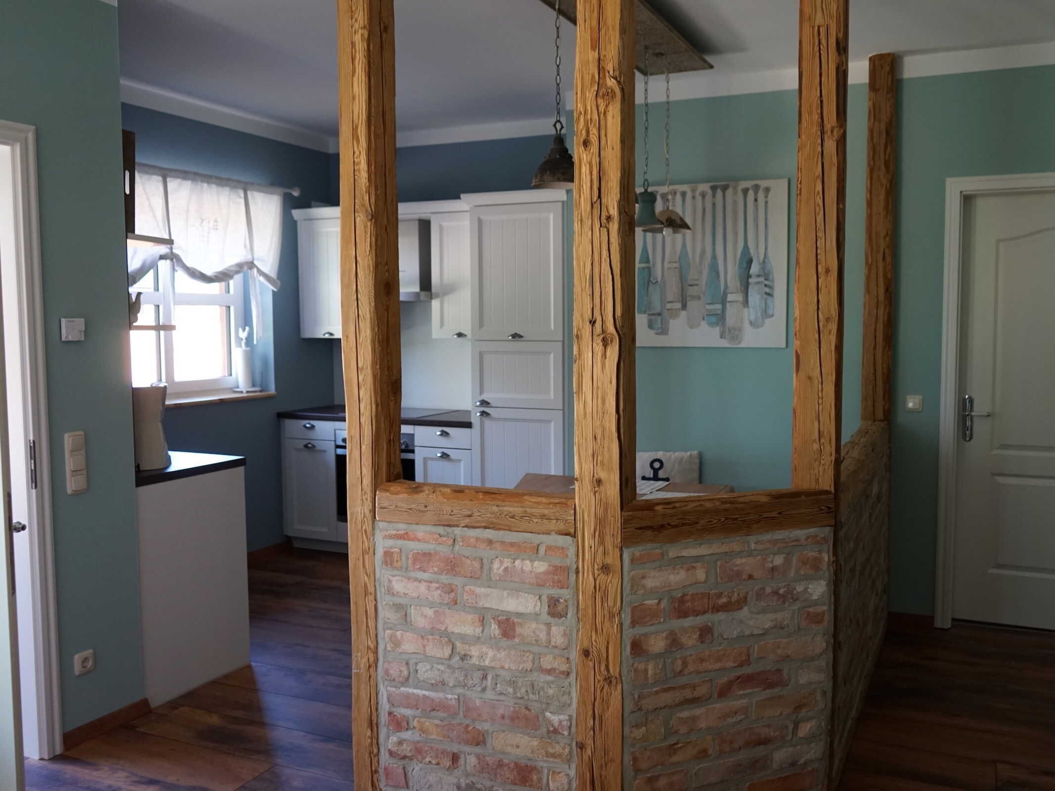 A kitchen with white cabinets, a brick accent wall, and a hanging light fixture.