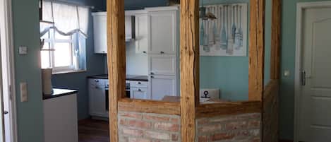 A kitchen with white cabinets, a brick accent wall, and a hanging light fixture.