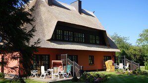 A thatched-roof house with a wooden staircase leading to a porch. - Bela Horse Farm - Suite 4 (Altenkirchen)