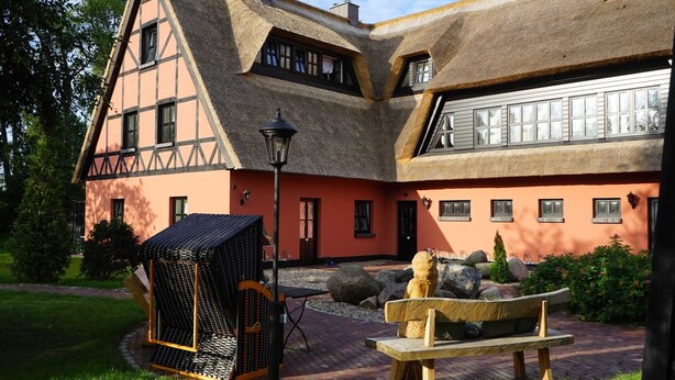 A traditional building with a thatched roof, a wooden bench, and a small garden area. - Bela Horse Farm - Suite 4 (Altenkirchen)