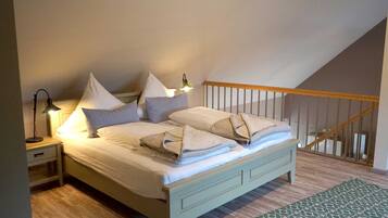 Ein Schlafzimmer mit einem Bett, Kissen, einem Nachttisch, einer Lampe und einem gemusterten Teppich.