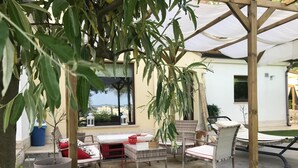 Une terrasse extérieure aménagée avec des meubles en osier, un auvent blanc et une vue sur le paysage urbain.