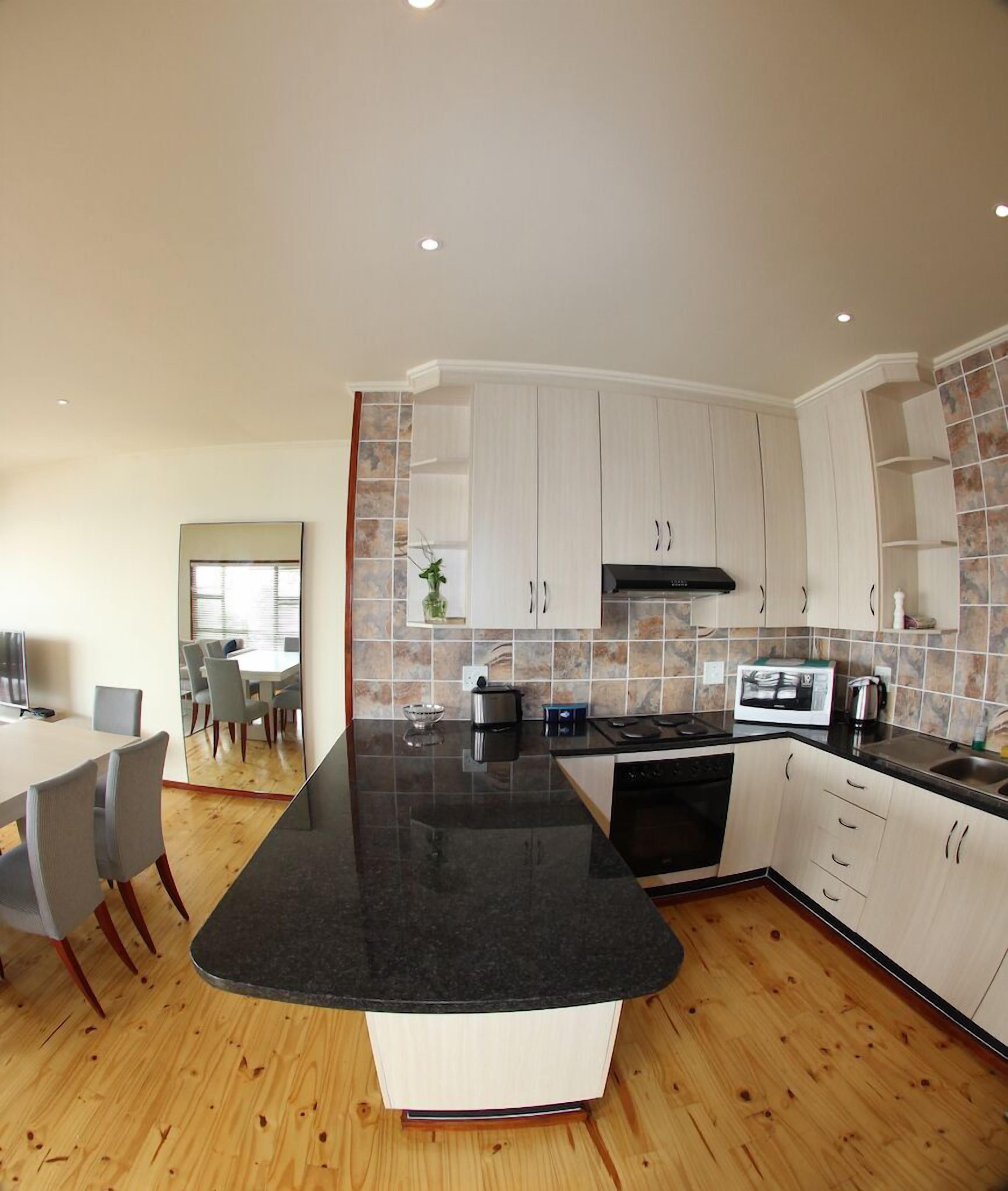 A modern kitchen with a large island, white cabinets, and a tiled backsplash.