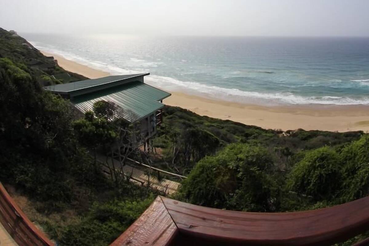 A beach view with a building on a hillside.