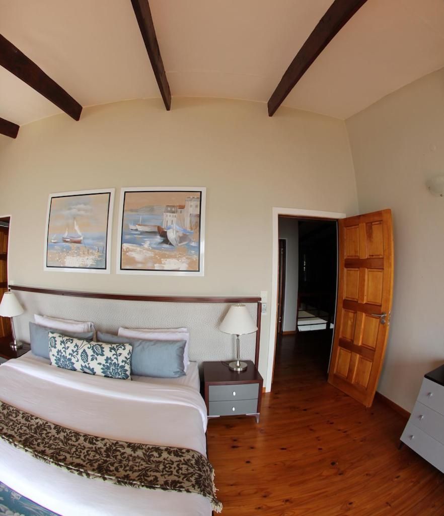 A bedroom with a bed, bedside tables, a nightstand, and a wooden door.