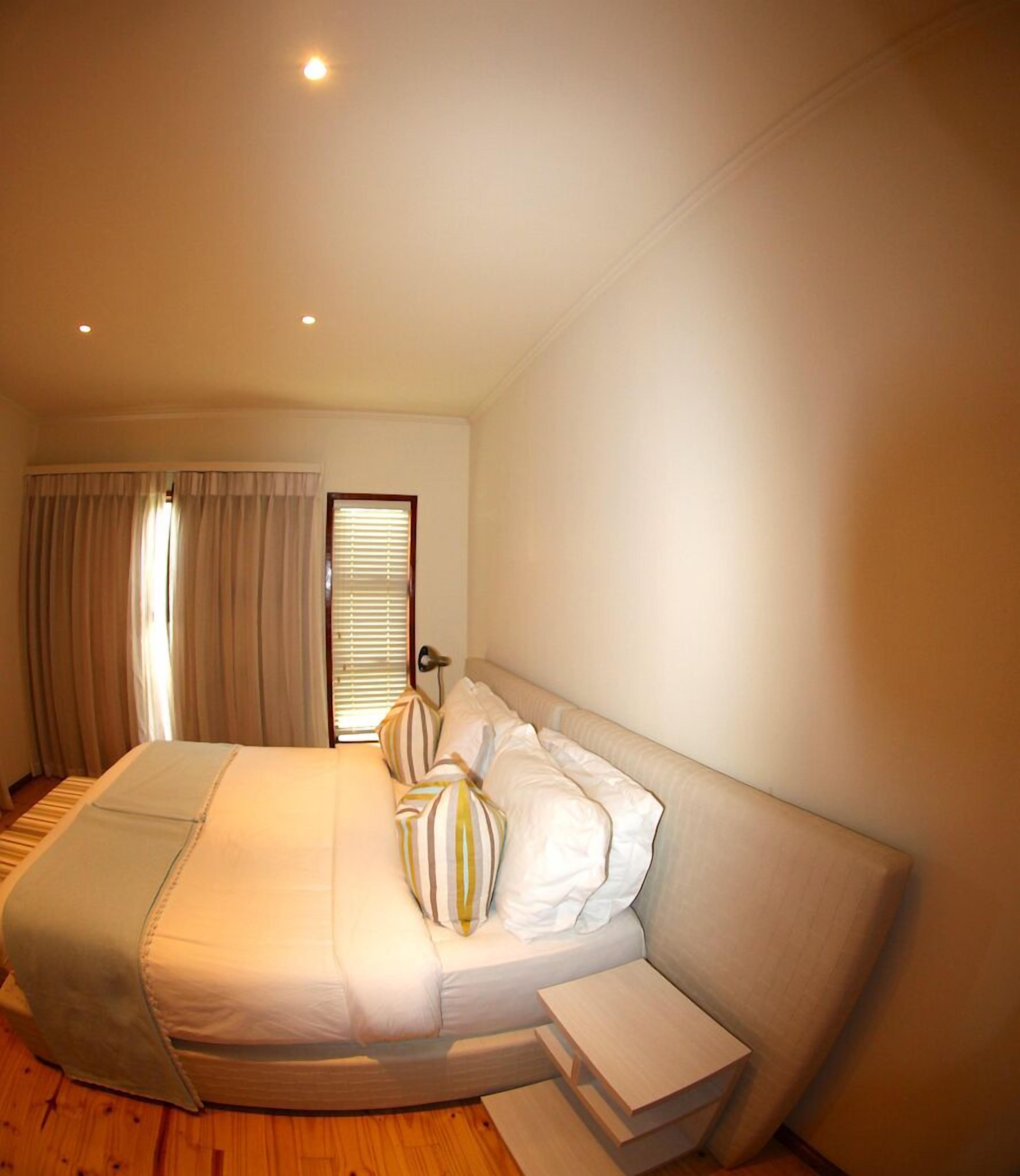 A bedroom with a large bed, a bedside table, and a window with curtains.