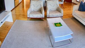Un salón amplio con televisor, una zona de comedor y una cocina al fondo.