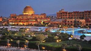 Un resort con un amplio espacio de piscina, un edificio en forma de cúpula y varias edificaciones hoteleras.