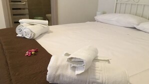 Una cama bien hecha con sábanas blancas y una colcha marrón.