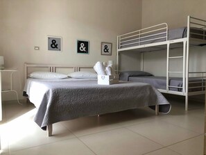 Habitación cuádruple Deluxe, varias camas, para no fumadores | 1 habitación, edredón, muebles diferentes y escritorio 