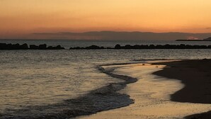 Escena de playa con un mar tranquilo, una orilla arenosa y un horizonte lejano.