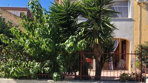 Un edificio con un muro de concreto, una cerca de metal y una palmera.