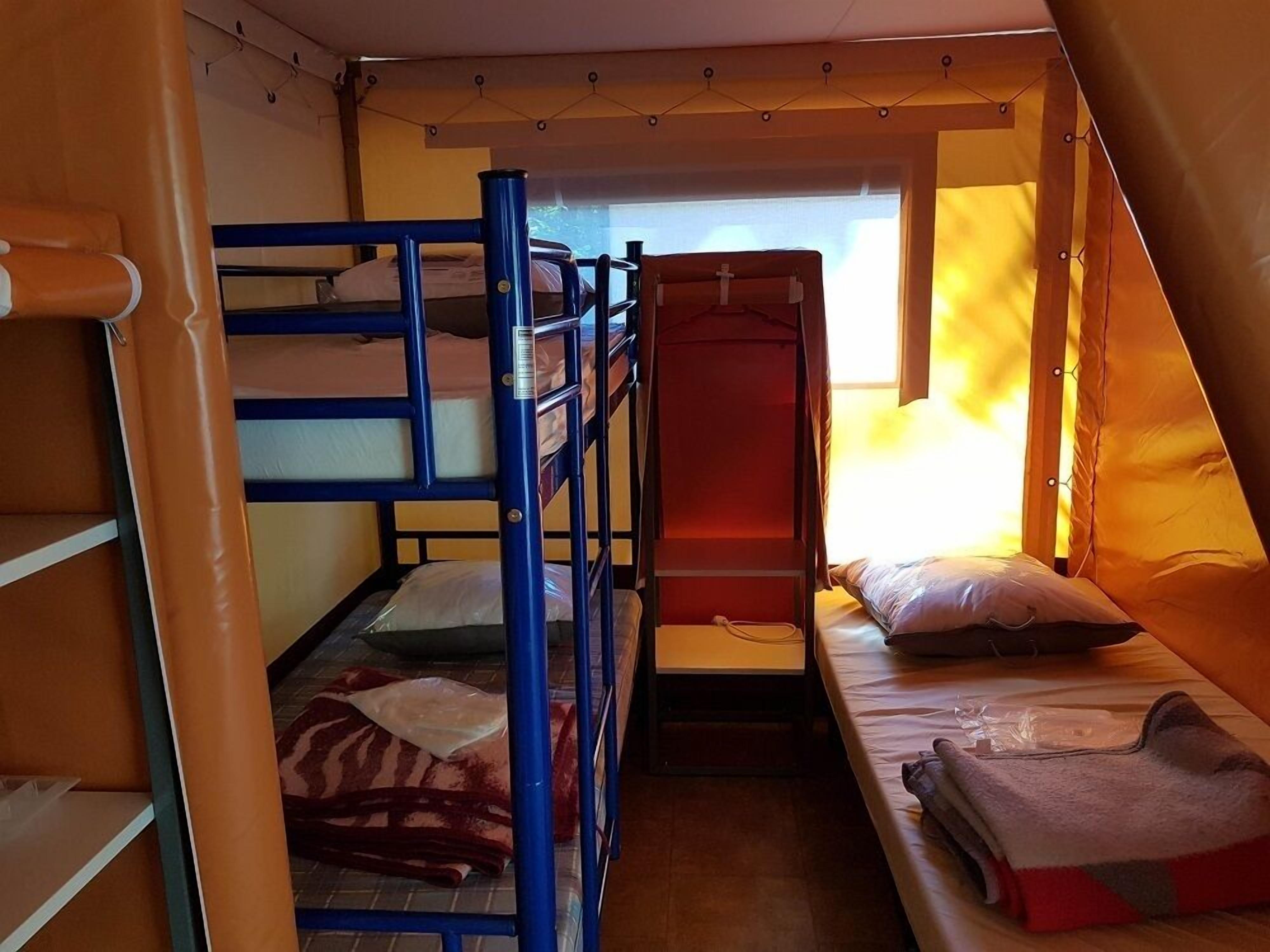 Una camera del dormitorio con letti a castello, una piccola finestra e una struttura simile a una tenda.