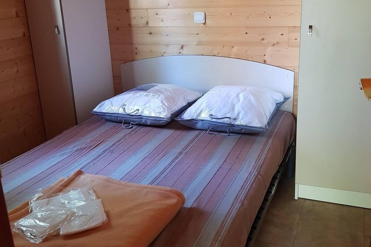 Una habitación pequeña y funcional con una cama individual, paredes de madera y un diseño sencillo.