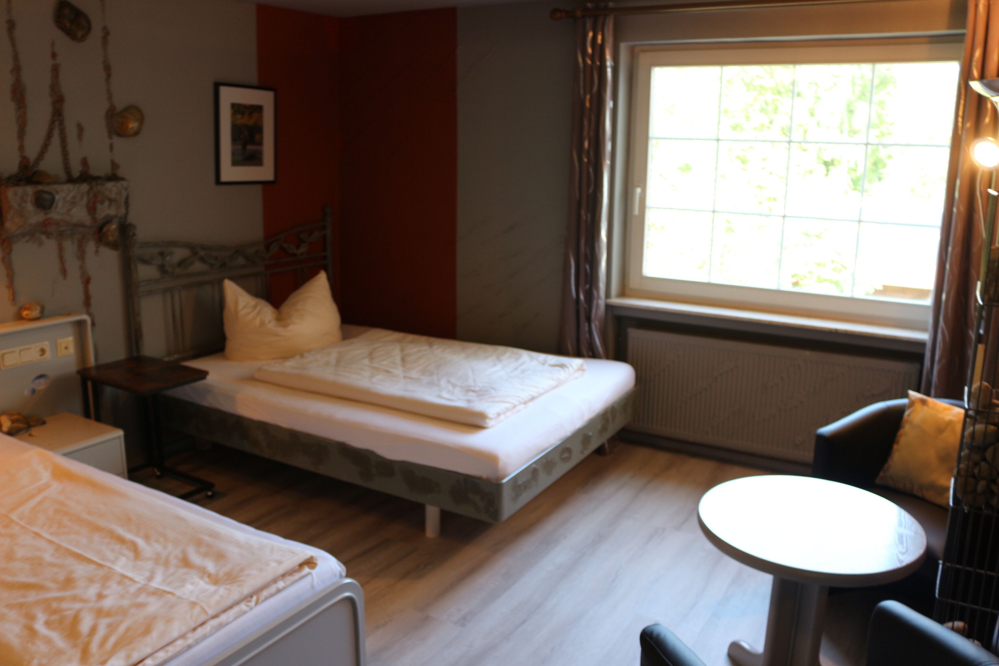 Een slaapkamer met een bed, nachtkastje en een raam met gordijnen.