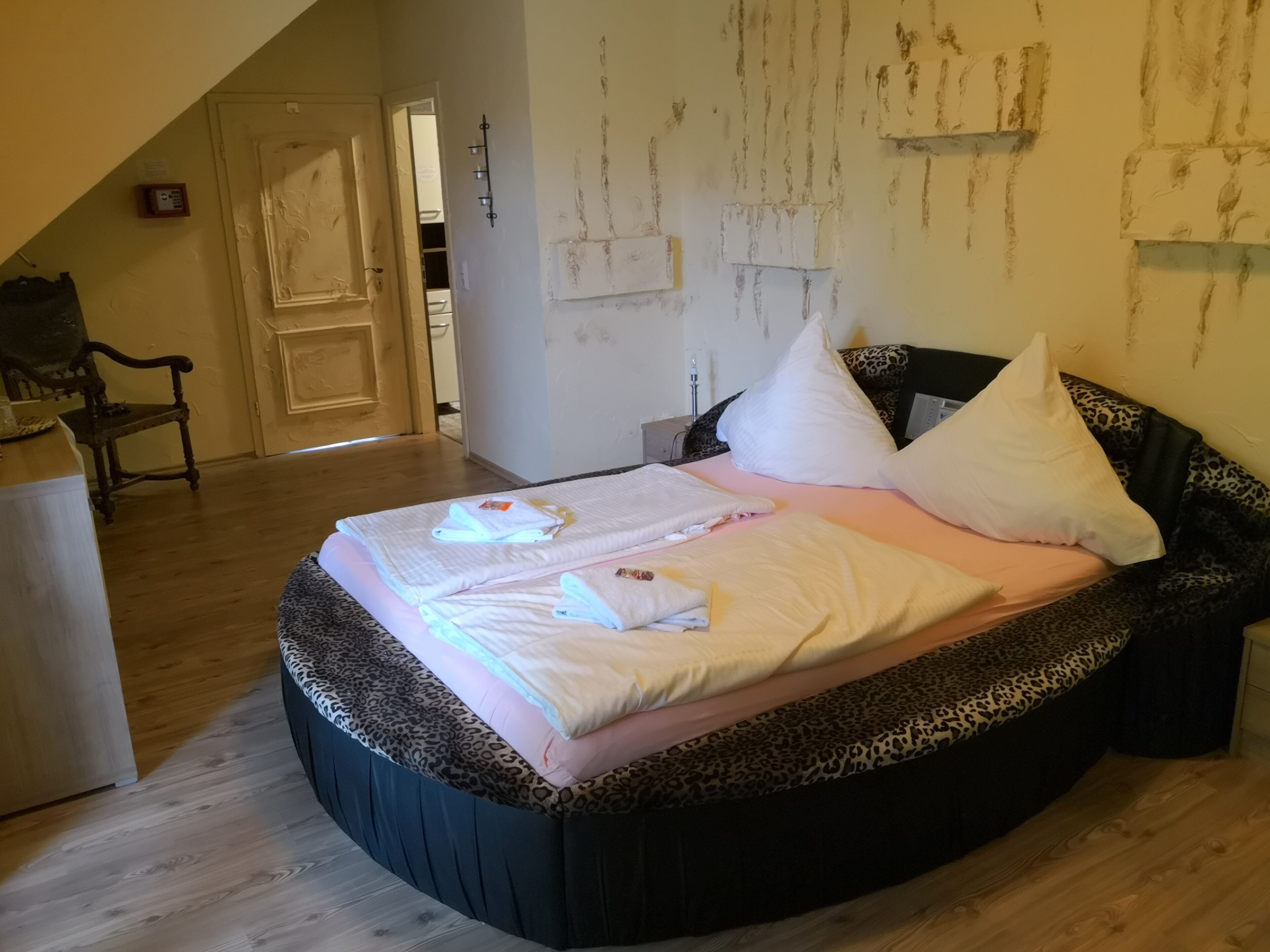 A bedroom with a bed, a chair, and a wardrobe.