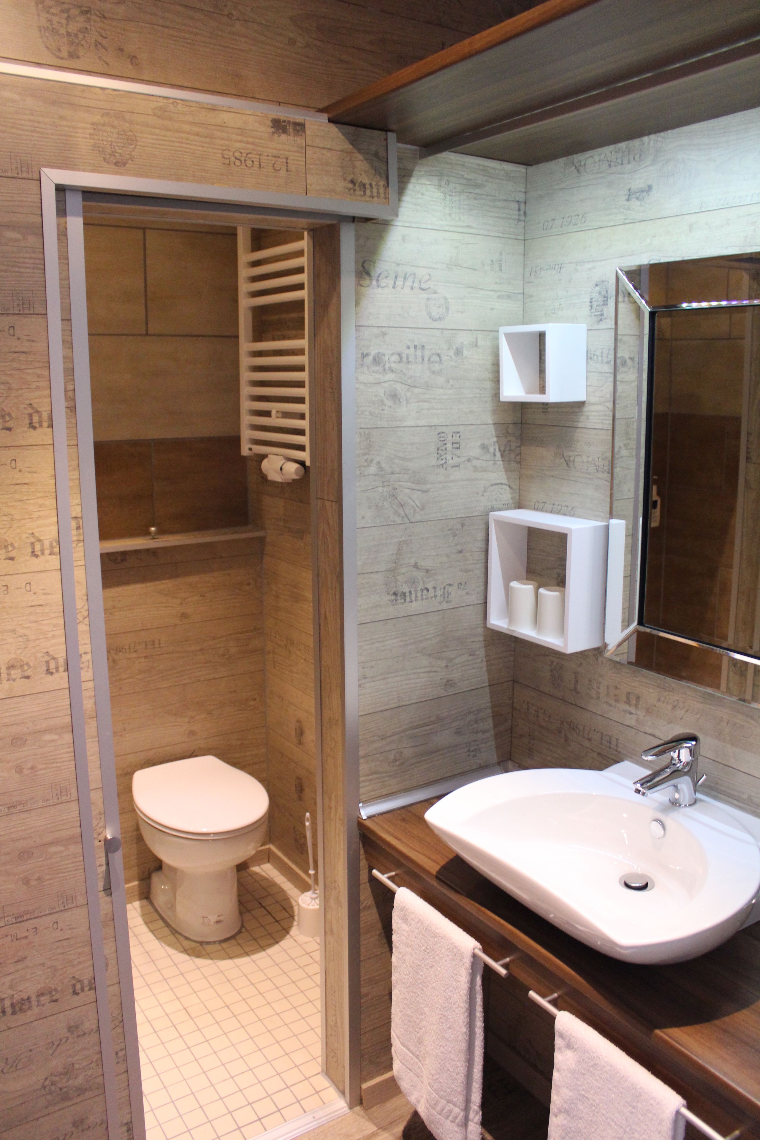 A bathroom with a wooden wall, a white toilet, a sink, and a mirror.