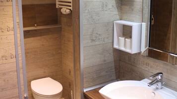 A bathroom with a wooden wall, a white toilet, a sink, and a mirror.