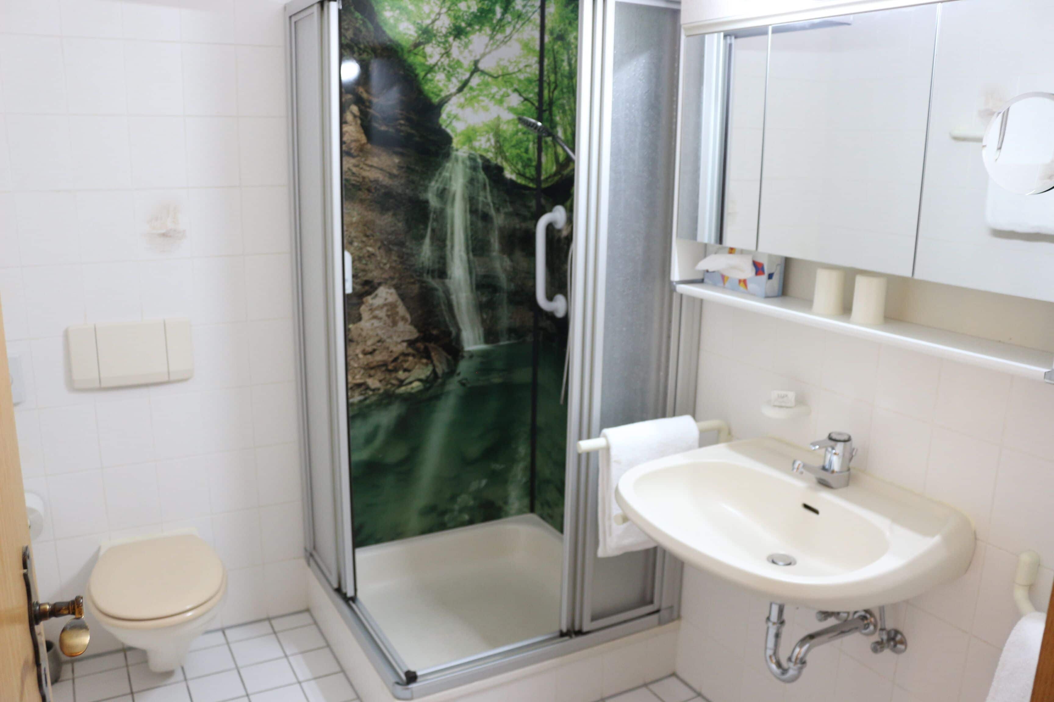 A bathroom with a glass-enclosed shower, a toilet, and a sink.
