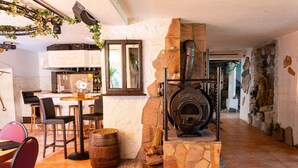 A rustic interior with a stone fireplace, wooden furniture, and a kitchen area. - Waldgasthaus am Schwarzenbruch (Allenbach)