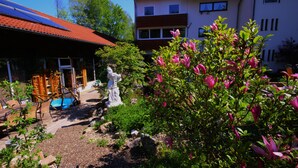 A garden with a statue, a pool, and a building with a red roof. - Waldgasthaus am Schwarzenbruch (Allenbach)