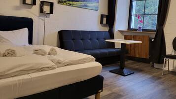 Ein Hotelzimmer mit einem Bett, einem Sofa, einem kleinen Tisch und einem Fenster mit Vorhängen.
