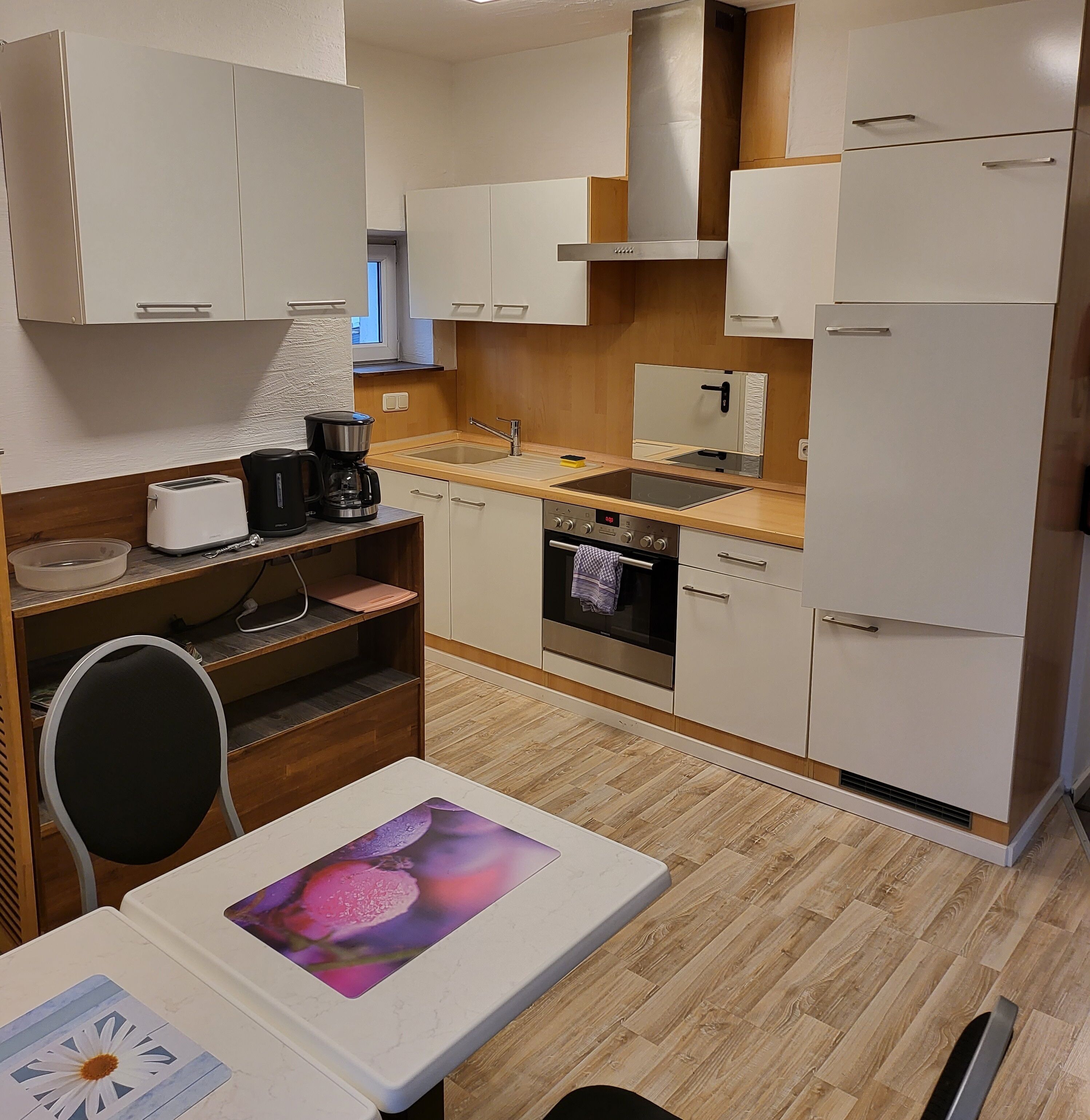 A compact kitchen with white cabinets, a stainless steel range, a built-in oven, and a sink.