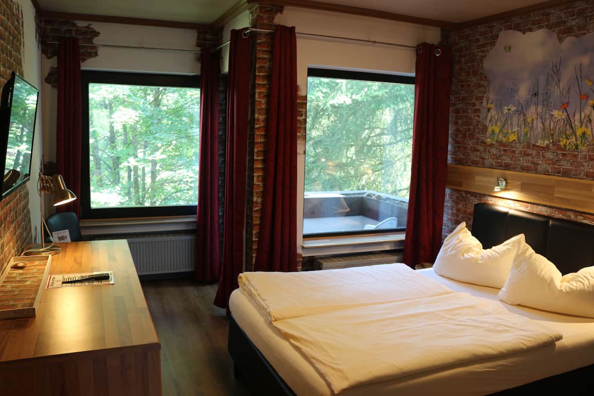 Hotellihuone, jossa on sänky, työpöytä, tuoli ja ikkuna, jossa on verhot.