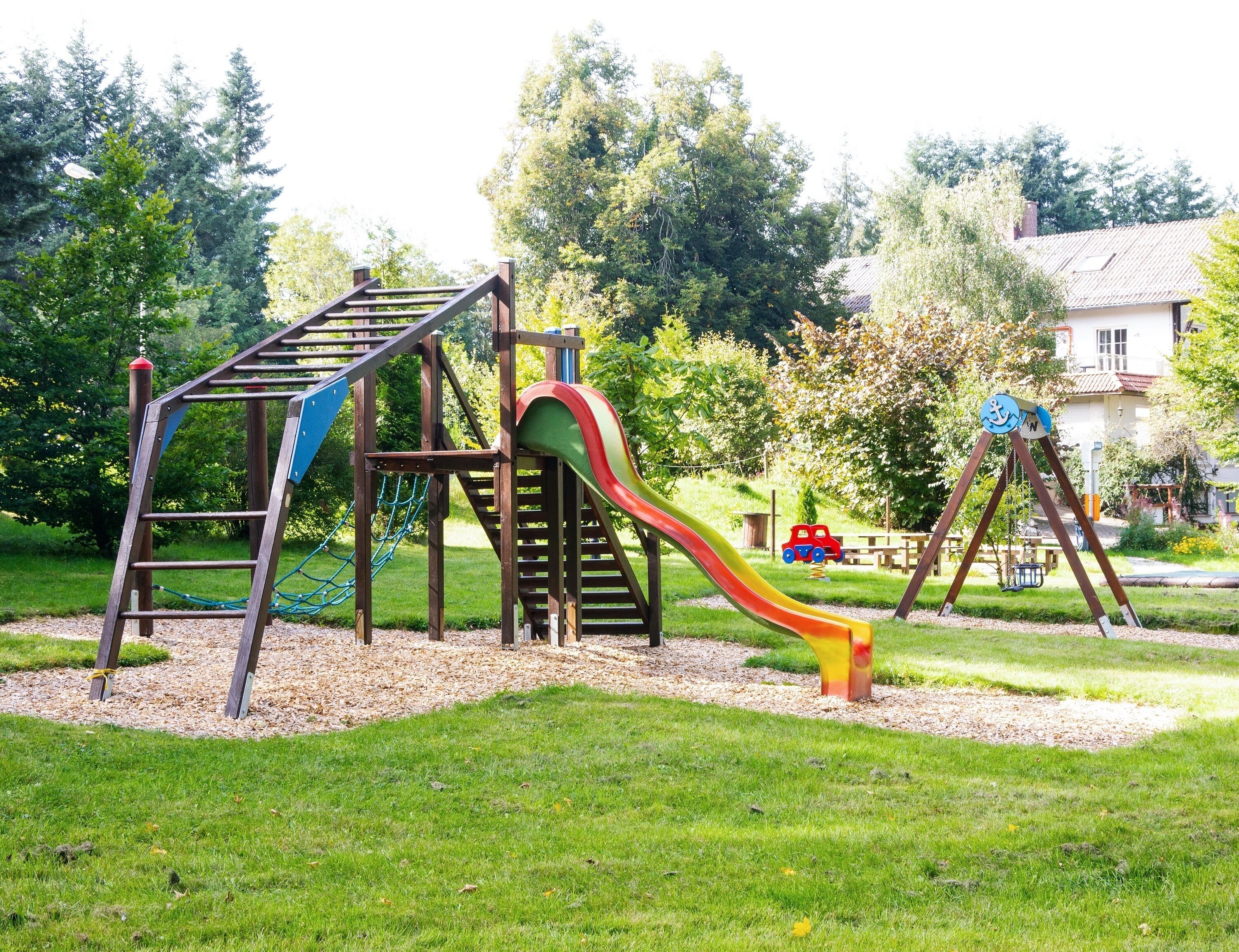 Ein Spielplatz mit Rutsche, Klettergerüsten und Schaukeln.