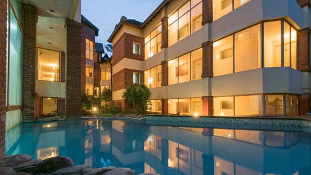 Um hotel de vários andares com piscina rodeada por pedras.