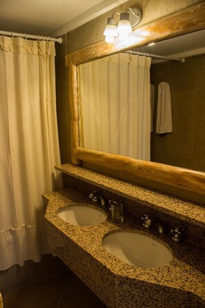 Une salle de bain avec deux lavabos, un miroir et un rideau de douche.