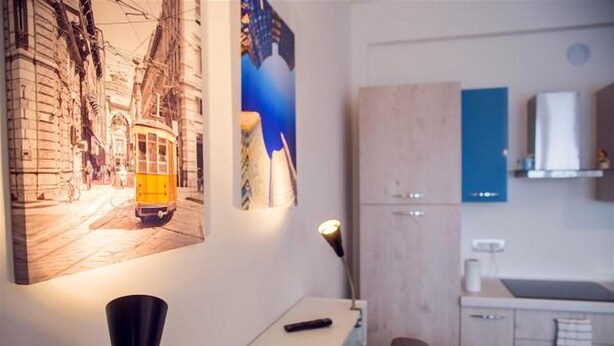 Une pièce moderne avec un canapé blanc, une petite table sur laquelle se trouve une télécommande et un meuble fixé au mur.