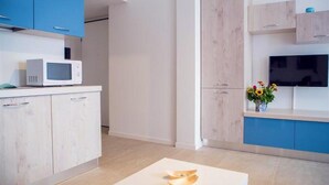 Une cuisine moderne avec des meubles bleus et en bois clair, un four à micro-ondes et un téléviseur à écran plat.