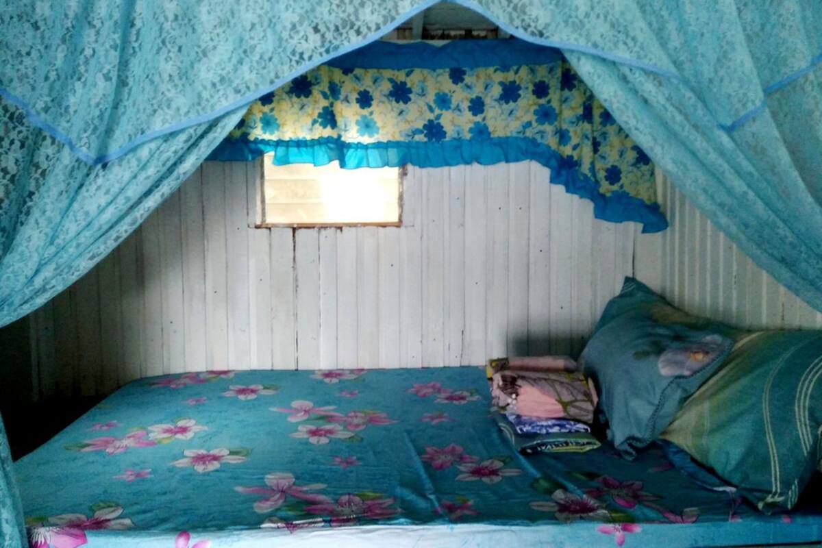 A small, enclosed sleeping area with a bed, a window, and a mosquito net.