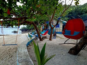 A beachside playground with swings, slides, and a red chair. - Bolo Beach Santorini (Alaminos)