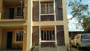 A multi-story residential building with balconies, large windows, and a parked car. - Marie's Sleep Transient House (Alaminos)