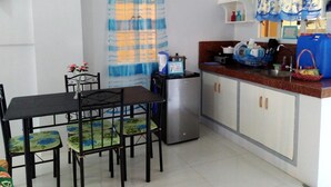 A compact kitchen with a dining table, chairs, a refrigerator, and a sink. - Marie's Sleep Transient House (Alaminos)