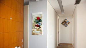 A hallway with a wooden door, a painting of fruit and flowers on the wall, and a small abstract art piece. - Unique AcropolisView HiEnd 2bdr (Athens)