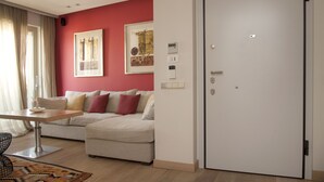 A modern living room with a sofa, a dining table, and a white door. - Unique AcropolisView HiEnd 2bdr (Athens)