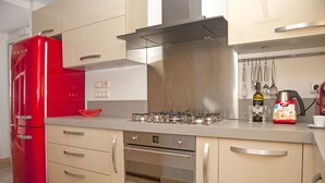 A modern kitchen with a red refrigerator, stainless steel appliances, and beige cabinetry. - Unique AcropolisView HiEnd 2bdr (Athens)