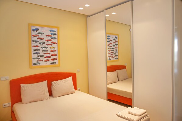 A hotel room with a bed, a mirror, and two framed pictures on the wall.
