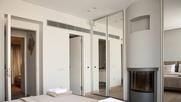 A modern hotel room with a large bed, a fireplace, and a mirror wall. - Unique AcropolisView HiEnd 2bdr (Athens)