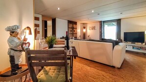 Un salon moderne comprenant un coin repas, un canapé, un téléviseur et un plancher en bois.