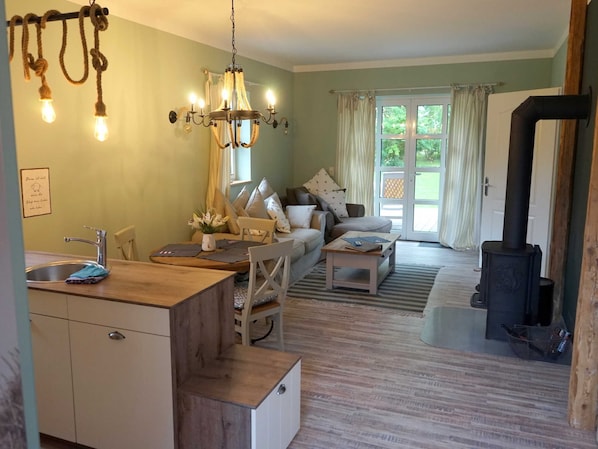 Ein gemütliches Wohnzimmer mit Sofa, Esstisch und Küchenzeile inklusive Spüle und Schränken.