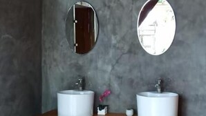 A bathroom with two white sinks, a wooden vanity, and two round mirrors on the wall.
