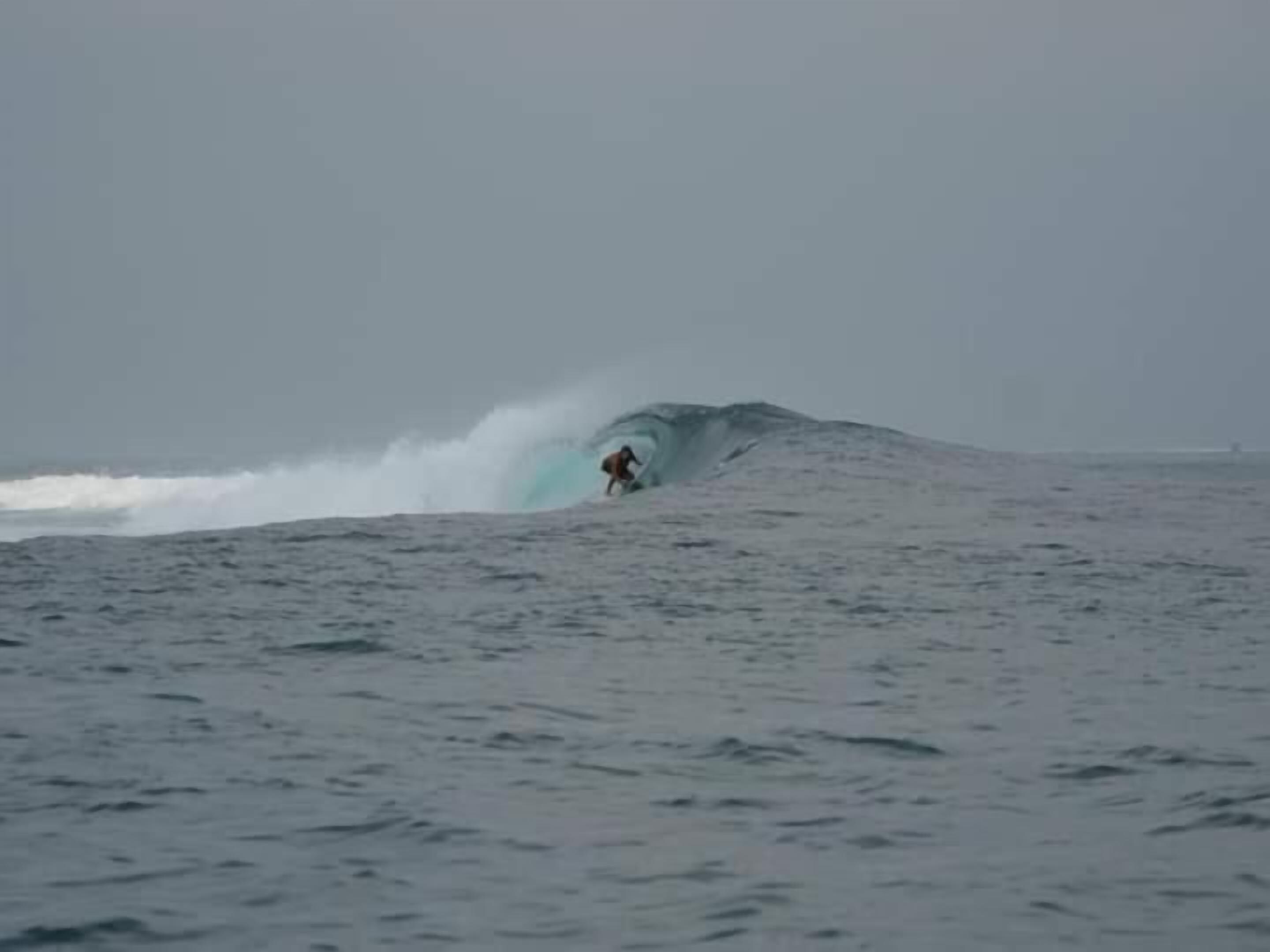 A person surfing a large wave in the ocean.