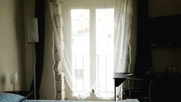 Ein Hotelzimmer mit Bett, Schreibtisch, Stuhl und einem Fenster mit Vorhängen.